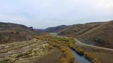 Vadiden ve dağlardan akan nehrin havadan görünüşü. Toprak yol manzarası, sarı çayır, tepeler ve Patagonya 'daki kayalık uçurum..