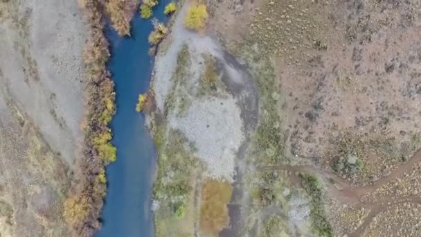 谷と山の間を流れる川の空中ビュー パタゴニアの未舗装道路 黄色の牧草地 丘や岩の崖の景色 — ストック動画