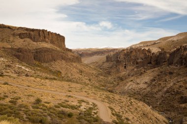 Vadinin karşısındaki toprak yolda ilerliyoruz. Dağların tepelerinde ve sarı çayırlarda yol. 