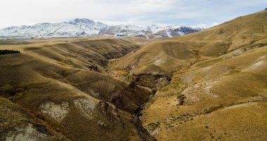 Kırsal alan. Dik uçurumlar ve sarı çayırlar. Dağlardaki altın vadi boyunca akan nehrin havadan görünüşü. 
