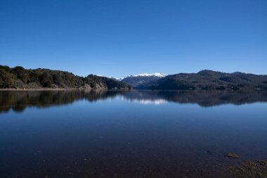 Villa Pehuenia, Patagonya Arjantin 'deki Batea Mahuida volkanı, And Dağları, orman ve Alumine Gölü manzarası. Güzel manzara ve mavi gökyüzü buzul sularında yansıyor..