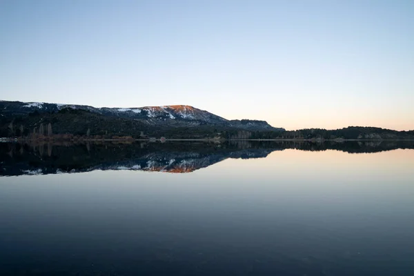 stock image Enchanting view of the placid lake at sunset. The mountains, forest and blue sky reflection in the water. 