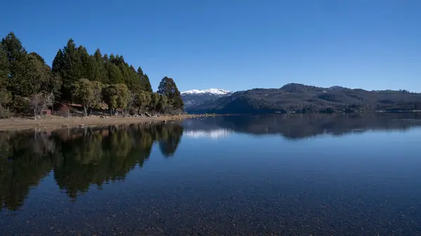 stock image View of volcano Batea Mahuida, Andes mountains, forest and Alumine lake in Villa Pehuenia, Patagonia Argentina. Beautiful landscape and blue sky reflection in the glacier water.