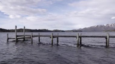 Huzurlu göldeki ahşap rıhtım manzarası. Arka plandaki Alpler.