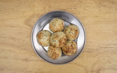 Küçük, fırınlanmış, peynir aromalı ruloların yakın görüntüsü, chipa olarak adlandırılır, ahşap arka planda metal bir çanakta.