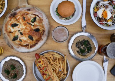 Ziyafet. Yemek hazır. Restoranın ahşap masasında çeşitli gurme yemekleri, sofra takımları ve bira bardaklarının üst görüntüsü..