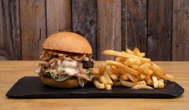 Canavar burger. Mozarella peynirli çok katmanlı hamburger, et, salatalık turşusu, mayonez, marul ve kızarmış soğanlı patates kızartması..