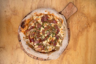 Domates soslu pizza, mozzarella peyniri, kıtır pastırma ve soğan, ahşap arka planda..