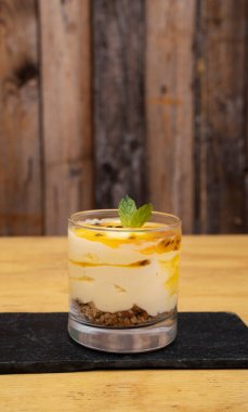 Meyveli tatlılar. Tutkulu meyve köpüklü, yulaf ezmeli ve fındıklı bir bardağın yakın görüntüsü.. 