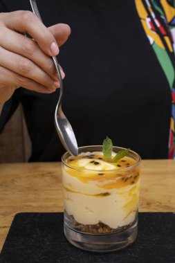 Tatlı yiyorum. Yakından bakınca, elinde kaşık olan bir kadının elinde yulaf ezmeli ve fındıklı tutkulu meyveli bir krema olduğunu görüyoruz..