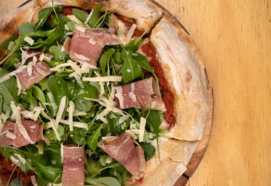 Arugula soslu pizza, jambon, parmesan peyniri, mozzarella peyniri ve domates sosu, ahşap masada.. 
