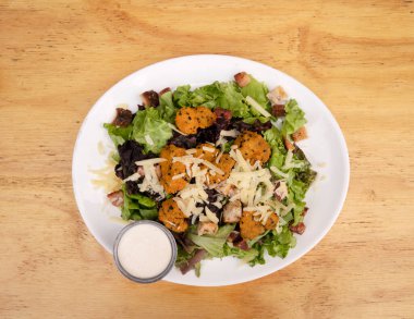 Kızarmış karides, marul, parmesan peyniri, ekmek ve kızarmış pastırma ile Sezar salatasının üst görüntüsü.. 