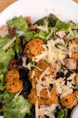 Kızarmış karides, marul, parmesan peyniri, ekmek ve kızarmış pastırma ile Sezar salatasının üst görüntüsü.. 