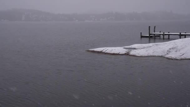 パタゴニアの風景 落ち着いた湖の上に降る雪の様子 水の中にある木製のドック 地平線の山と森の間違ったイメージ — ストック動画