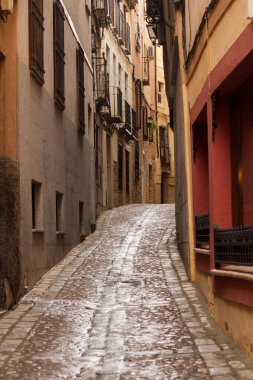 Şehir manzarası. Tarih ve mimari. Eski tasarımlı renkli binalar. İspanya 'da, Toledo' da dar bir sokak ve yağmurdan sonra ıslak bir sokak görünüyor.. 