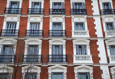 Şehir mimarisi ve tasarımı. Dairenin yakın görüntüsü tuğla duvar cephesi, pencereler ve Fransız balkonları..
