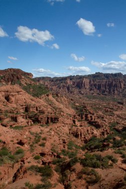 Dik kanyon. Kızıl çöl manzarası, uçurumlar, turuncu kumtaşı oluşumları ve ufuktaki kayalık dağlar.