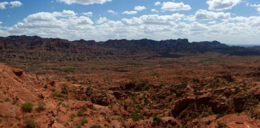 Büyük Kanyon. Kızıl çöl manzarası, uçurumlar, kumtaşı oluşumları ve ufuktaki kayalık dağlar..