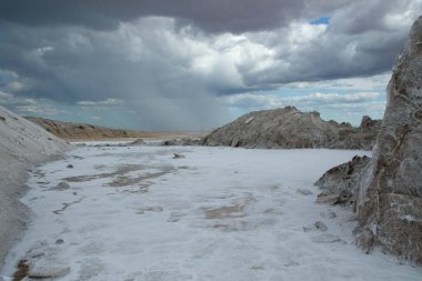 Doğal tuz düzlükleri. Endüstri ve açık döküm madencilik. Dramatik ve fırtınalı bir gökyüzü altında tuzlu ve doğal tarlalar.
