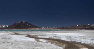 And Dağları 'ndaki volkanik manzara. Yeşil Göl adı verilen turkuaz renkli gölün panorama manzarası. Kordillera 'nın yükseklerinde, karlı zirveleri ve volkanları olan karanlık dağlar..