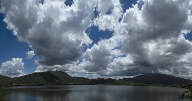 Potrero de los Funes, Arjantin 'in panorama manzarası. Yeşil orman, tepeler ve göl dramatik bir gökyüzünün altında güzel bulutlarla.