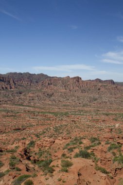 Dik kanyon. Kızıl çöl manzarası, uçurumlar, turuncu kumtaşı oluşumları ve ufuktaki kayalık dağlar San Luis, Arjantin 'deki Sierra de las Quijadas Ulusal Parkı.