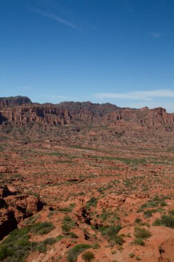 Dik kanyon. Kızıl çöl manzarası, uçurumlar, turuncu kumtaşı oluşumları ve ufuktaki kayalık dağlar San Luis, Arjantin 'deki Sierra de las Quijadas Ulusal Parkı.