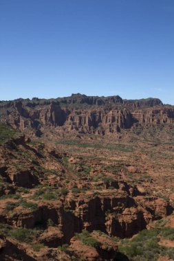 Dik kanyon. Kızıl çöl, uçurumlar, turuncu kumtaşı oluşumları ve ufuktaki kayalık dağlar San Luis, Arjantin 'deki Sierra de las Quijadas Ulusal Parkı.