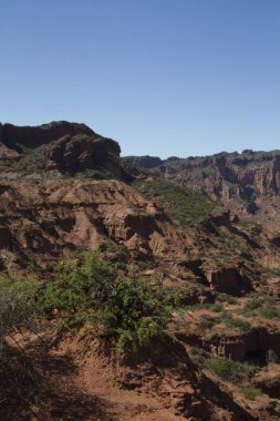 Dik kanyon. Kızıl çöl, uçurumlar, turuncu kumtaşı oluşumları ve ufuktaki kayalık dağlar San Luis, Arjantin 'deki Sierra de las Quijadas Ulusal Parkı.