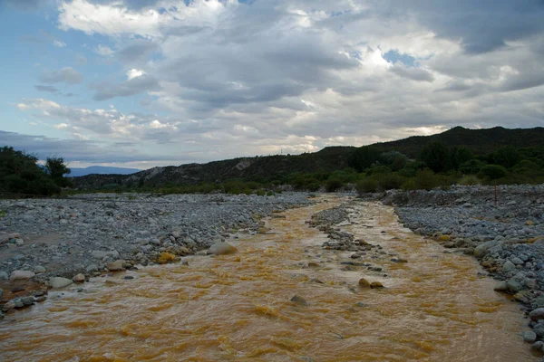 Unique yellow river called River of Gold due to the presence of iron, flowing along the rocky valley in La Rioja, Argentina.