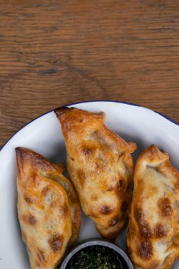 Geleneksel Arjantin yemekleri. Chimichurri soslu börekler ahşap masada beyaz bir kâse içinde.. 