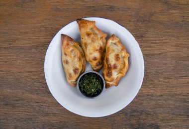 Geleneksel Arjantin yemekleri. Chimichurri soslu börekler ahşap masada beyaz bir kâse içinde.. 