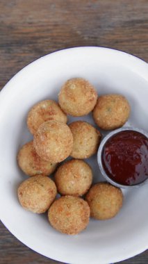 Peynir topları. Patates ve mozzarella peynirli kroket, ahşap masada beyaz bir kasede acı biber soslu..