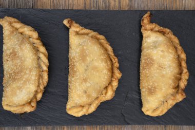 Geleneksel et kızartması. Tahta masadaki siyah tabakta üç doldurulmuş turtanın en üst görüntüsü..