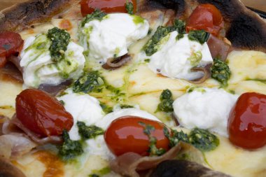 Mozarella, burrata peyniri, vişneli domates ve jambonlu pizzanın yakın görüntüsü..