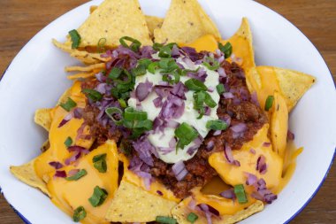 Acı biberli cips. Çedar peynirli nachos, avokado kremi, kırmızı soğan turşusu ve beyaz kasede et sosu..