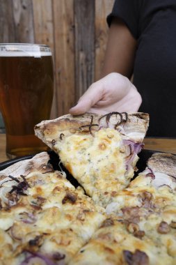 Restoranda pizza yiyorum. Mozarella, peynir ve soğanlı bir dilim pizzayı tutan bir kadının yakın görüntüsü..