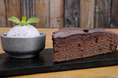 Fırın ve tatlılar. Yakından bakınca, bir dilim çikolatalı pastanın üzerinde siyah bir tabakta dondurması var..