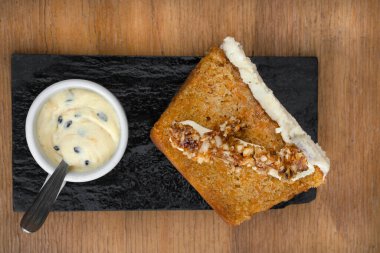 Tatlı tatlılar. Restoranın ahşap masasındaki siyah bir tabakta tutkulu meyveli kremalı havuçlu kekin üst görüntüsü.. 