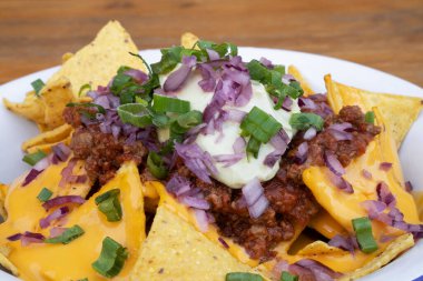 Acı biberli cips. Çedar peynirli nachos, avokado kremi, kırmızı soğan turşusu ve beyaz kasede et sosu..