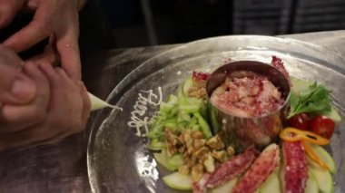 Gastronomi. Deniz ürünleri. Erkek aşçı boru çantasıyla dekore ediyor. Restoranın mutfağında taze Örümcek Yengeci tabağı var..