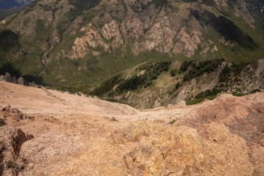 Tepenin tepesinden kayalık uçurumun, ormanın ve sarp dağların manzarası. 
