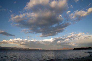Nahuel Huapi Gölü ve ufuktaki And Dağları 'nın manzarası, dramatik bir gökyüzünün altında, sabahın erken saatlerinde.. 