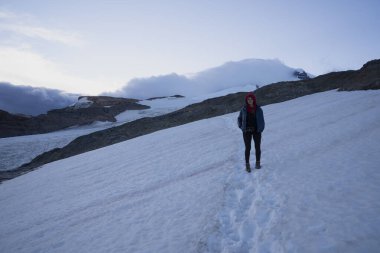 Tronador tepesinde karda yürüyüş yapan bir kadın. Glacier Castano Overo 'nun ve güneşin doğuşundaki dağın manzarası. 
