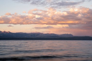 Gün batımında Nahuel Huapi Gölü ve And Dağları 'nın uzun pozlu görüntüleri. Güzel bulanık su efekti, kayalık kıyı ve alacakaranlık rengi gökyüzünde. 