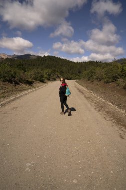 Güneşli bir yaz gününde ormanda ve tepelerde yürüyüş yapan genç bir kadının görüntüsü.. 