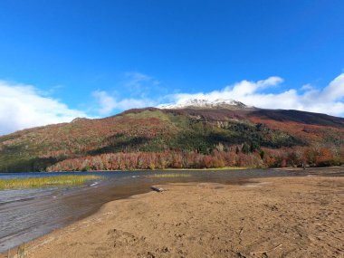 Falkner Gölü manzarası, kumlu plaj, sonbaharda dağlar ve orman, San Martn de los Andes, Patagonya, Arjantin. Ağaçların yapraklarında güzel sonbahar renkleri.