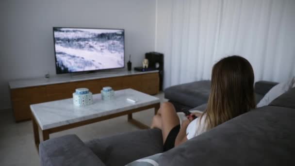 Frau Sitzt Auf Dem Sofa Vor Dem Fernseher — Stockvideo