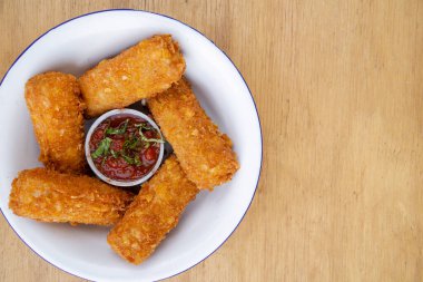 Kızarmış mozarella peynirinin üst görüntüsü kırmızı baharatlı sosla ahşap masadaki beyaz kasede..