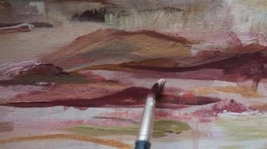 Sanat yapmak. Stüdyoda resim yapmak. Hareket atışı. Resim fırçasını manipüle eden bir sanatçının yakın görüntüsü. Akrilik kahverengiyle resim yapmak dağları resmeden doğal bir manzara..